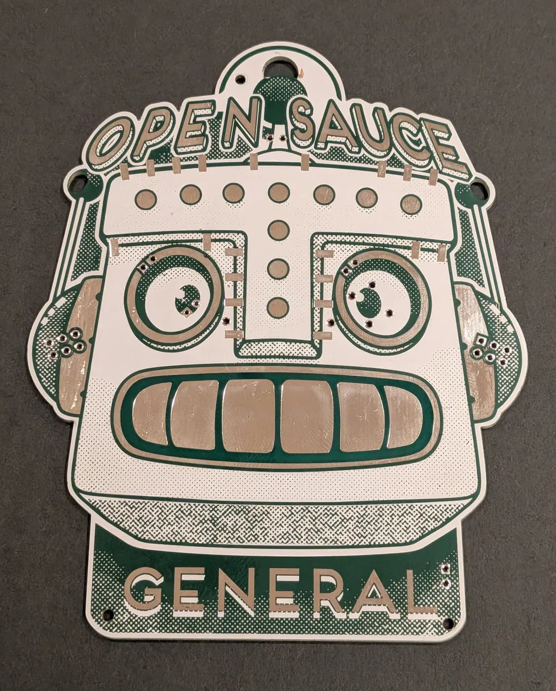 The bare Open Sauce 2026 badge, face up with the lanyard removed